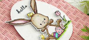 pink hand made Easter card with a white egg shaped frame and a brown bunny with a chick on his head and Easter eggs by his feet