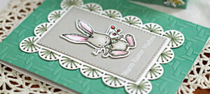 handmade greeting card with a mint card base, a white scalloped stitch boarder and a colored easter bunny in the center