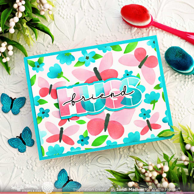 stenciled handmade card with pink butterflies and teal flowers with green leaves and a hugs sentiment overlay 