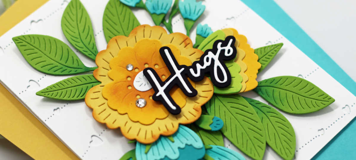 yellow, teal and green floral die cut card with a black and white die cut sentiment and clear rhinestone embellishments