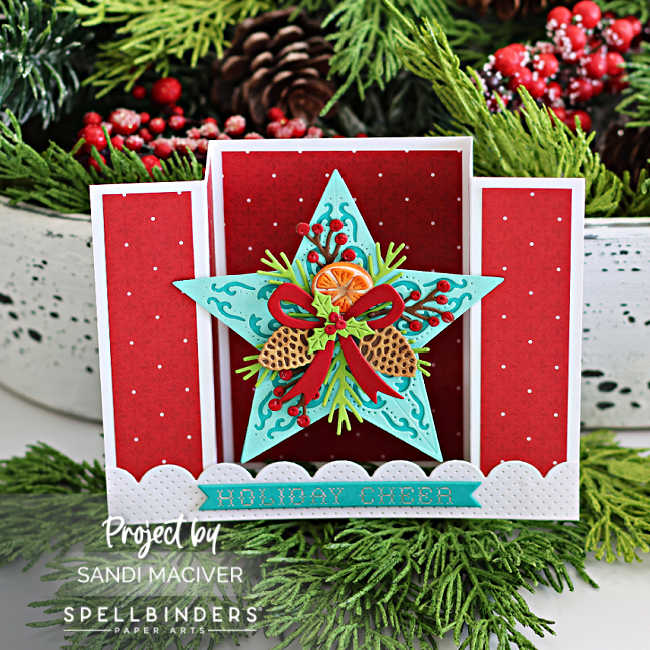 Handmade Christmas bridge card featuring a large dimensional teal star with die-cut pinecones, berries, holly, and a red bow on a red polka dot background. White pierced scalloped borders and a ‘Holiday Cheer’ sentiment complete the festive pop-up design by Sandi MacIver using Spellbinders products