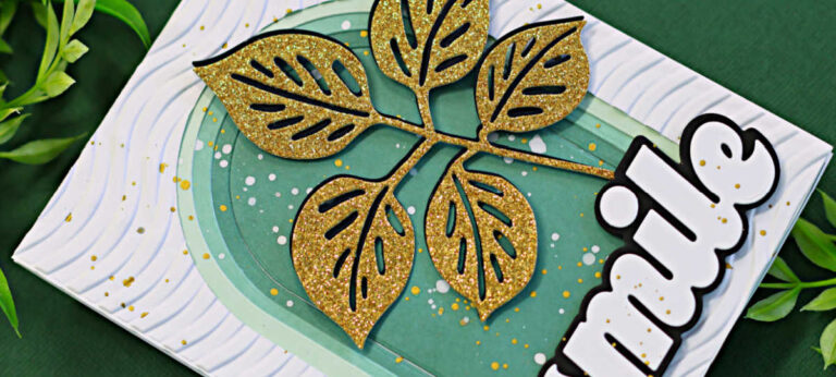 Handmade card featuring a layered arched background in gradient green tones with white splattered paint accents. A glittery gold die-cut branch with six leaves is centered on the card. The white embossed card base has a subtle wavy pattern, and the bold black-and-white sentiment "smile" is positioned vertically along the right side. Gold and white paint splatters add a touch of texture and visual interest.