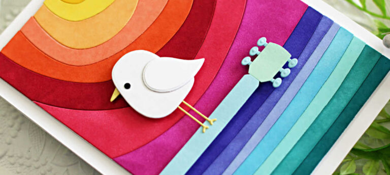 Handmade card inspired by the iconic Woodstock Festival poster, featuring the Simon Says Stamp Ocean Horizon die set. A white die-cut bird from the Birdies die set perches on a stylized guitar neck, recreating the vintage 1969 design in bold rainbow colors.