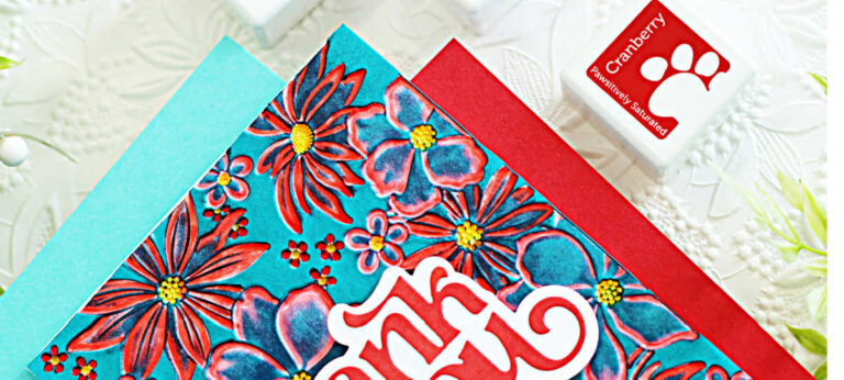 Handmade thank you card created with the Simon Says Stamp Blossom Burst embossing folder and Fancy Thank You sentiment die. The background features the blackout technique with Ocean ink, highlighting red and purple flowers with yellow centers against a teal backdrop. A bold layered red and white “thank you” sentiment is centered on the card, adding dimension and contrast.