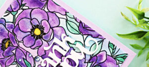 Handmade thank you card featuring the new Simon Says Stamp Delicate Blossoms stamp set, watercolored in vibrant shades of purple with green leaves, black heat-embossed outlines, and a bold white die-cut sentiment.