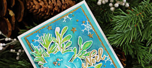 Christmas Card created with the NEW Simon Says Stamp and Tim Holtz Collaboration Festive Watercolor set. The background features a rich blend of Distress Oxide Sprays inEverygreenBough, Tumbled Glass, Mermaid Lagoon, Salvagged Patina, and Broken China. layered on top are bold watercolor-stype poinsettias in Surf, Ocean and Seafom Pawsitively Saturated Inks, with leaves in Pearfection and Ocean. The design is accented with glimmering gold stars and white heat embossed snowflakes, with a die-cut NOEL sentiment heat embossed in gold.