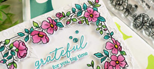 Handmade card created with the Simon Says Stamp and Pinkfresh STAMPtember collaboration stamp, die, and stencil set. The floral frame is colored in shades of pink and teal, with a sentiment reading ‘grateful for you, big time.’ The background is embossed with the Fun Floral Frame embossing folder from Simon Says Stamp, and the card is finished with teal gem embellishments.
