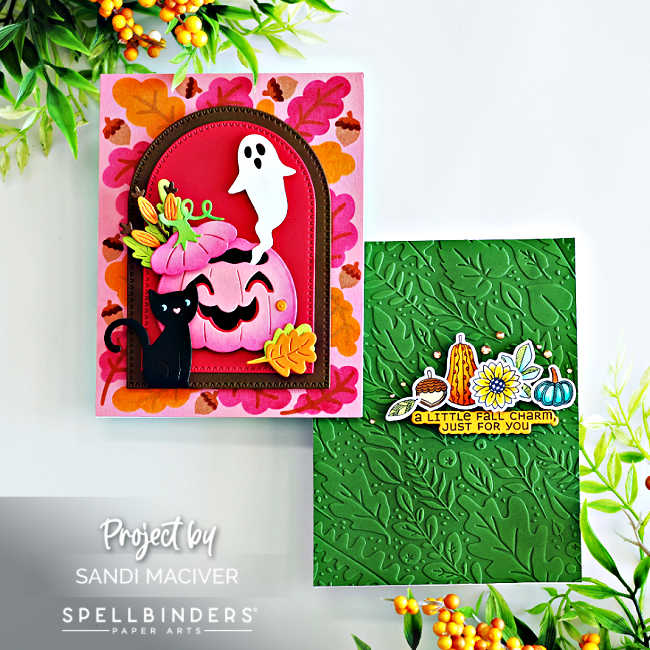 wo handmade fall-themed cards created with the Spellbinders September Club Kits. The card on the left features a pink and orange stenciled leaf background with a stitched arch die cut in deep red, decorated with a smiling pink jack-o’-lantern, black cat, ghost, yellow leaves, and floral accents. The card on the right has a deep green embossed leafy background with a cluster of stamped and die-cut fall elements, including a sunflower, pumpkin, gourd, acorn, and sentiment strip reading “A LITTLE FALL CHARM, JUST FOR YOU.” Both cards are styled with fall foliage and berries for a seasonal look.
