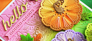 Handmade fall card created with the Spellbinders September Stitching Die Club. The design features three ink-blended pumpkins stitched with gold thread in shades of orange, green, and purple. The background is softly ink blended in pink, green, and gold tones, then embossed with the Autumn Breeze September Embossing Club folder. Additional die-cut autumn leaves accent the card, and the sentiment reads “hello gourd-geous” in gold.