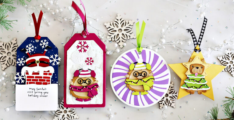 Four handmade holiday gift tags created with the Spellbinders Merry Mischief release. Designs include Santa’s suit over a chimney with snowflakes and sentiment, a cute critter bundled in a scarf and hat on an embossed snowflake background, a round tag with a striped backdrop featuring another winter critter, and a star-shaped tag with a festive animal dressed as a Christmas tree. Each tag is finished with colorful ribbons and surrounded by die-cut snowflakes for a festive holiday display.