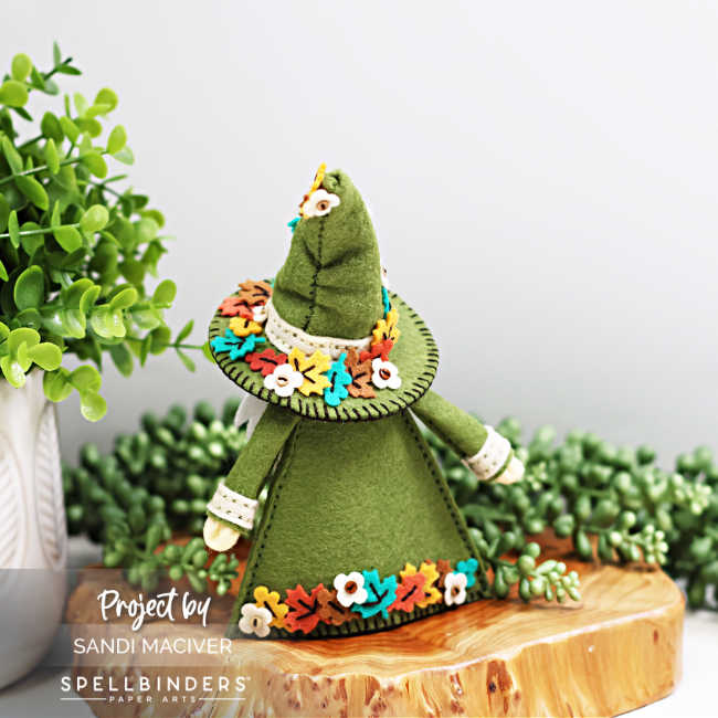 Back view of Fall Fergus the Gnome — handmade with the Spellbinders 3D Felt Décor Dies and Merino Wool Felt. The moss-green coat and tall hat are accented with colorful die-cut felt leaves and tiny flowers around the hem and hat brim, designed by Sandi MacIver for the Spellbinders 3D Felt Décor collection.