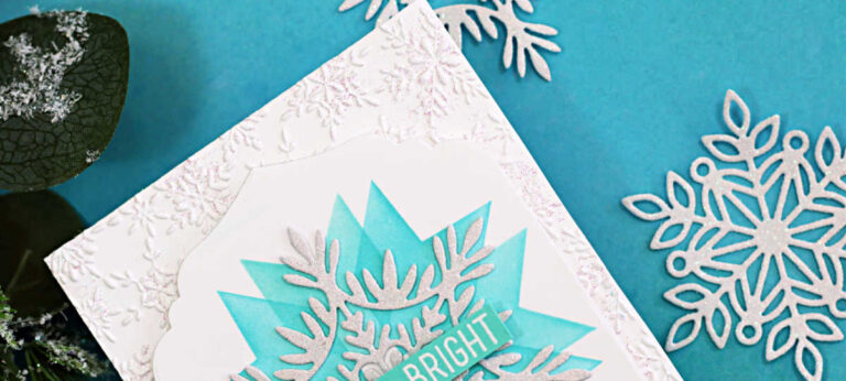 Handmade holiday card featuring a large layered snowflake design created with the Simon Says Stamp Patchwork Stencil, Willow Snowflake Die, Modern Teardrop Dies, and Label Slide Christmas Sentiment Stamps. The snowflake is glittered white and layered over a teal stenciled starburst background with a “Merry & Bright” sentiment across the center. The card base is embossed with the Cheery Snowflakes Embossing Folder, adding subtle texture and shimmer, and is styled with coordinating die-cut snowflakes and greenery for a festive winter look.