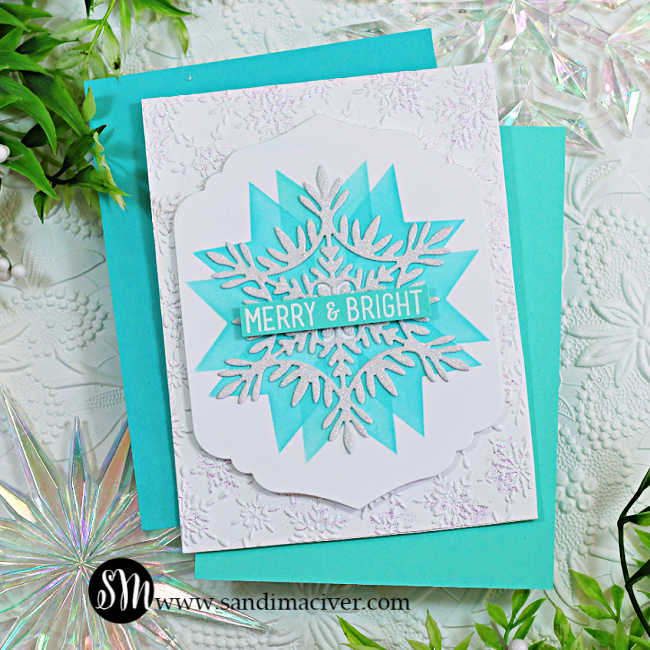Handmade holiday card featuring a large layered snowflake design created with the Simon Says Stamp Patchwork Stencil, Willow Snowflake Die, Modern Teardrop Dies, and Label Slide Christmas Sentiment Stamps. The snowflake is glittered white and layered over a teal stenciled starburst background with a “Merry & Bright” sentiment across the center. The card base is embossed with the Cheery Snowflakes Embossing Folder, adding subtle texture and shimmer, and is styled with coordinating die-cut snowflakes and greenery for a festive winter look.