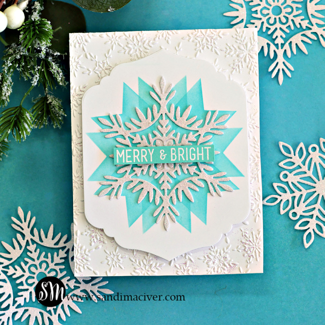 Handmade holiday card featuring a large layered snowflake design created with the Simon Says Stamp Patchwork Stencil, Willow Snowflake Die, Modern Teardrop Dies, and Label Slide Christmas Sentiment Stamps. The snowflake is glittered white and layered over a teal stenciled starburst background with a “Merry & Bright” sentiment across the center. The card base is embossed with the Cheery Snowflakes Embossing Folder, adding subtle texture and shimmer, and is styled with coordinating die-cut snowflakes and greenery for a festive winter look.