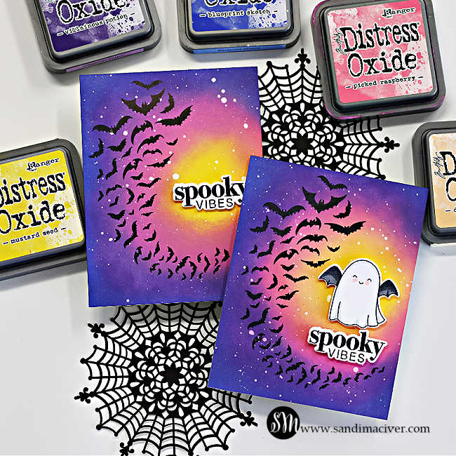 Handmade Halloween card featuring a bold ink-blended background created with Distress Oxide inks. The design showcases a swarm of black bats spiraling across a glowing yellow moon, fading into pink and purple night sky tones. White paint splatters add a starry effect, and the sentiment “spooky vibes” is die cut and layered in black and white at the center. Card designed by Sandi MacIver using the Simon Says Stamp Halloween Basics Stamp and Die Set.