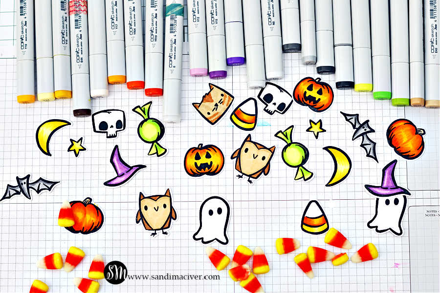 A collection of adorable Halloween images stamped and colored with Copic markers from the Tim Holtz Tiny Frights Stamp Set by Simon Says Stamp. The cut-out pieces include pumpkins, ghosts, owls, bats, moons, stars, skulls, candy corn, witch hats, and wrapped candies in bright shades of orange, yellow, green, and purple. The artwork is arranged on a grid-lined crafting mat surrounded by Copic markers and scattered candy corn, ready to be used for Halloween treat tags or cards.