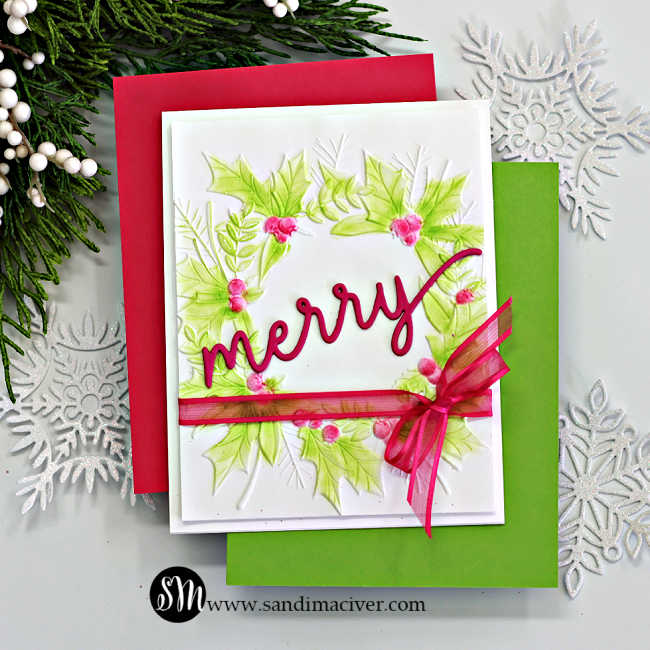 Handmade Christmas card featuring the Simon Says Stamp Festive Wreath Embossing Folder, ink-blended with soft green and pink hues to highlight the raised holly leaves and berries. The card is finished with a bold pink “merry” die-cut sentiment from the Holiday Duo Die Set and accented with a sheer pink ribbon bow tied around the panel. Layered on red and green cardstock for a festive, elegant presentation.