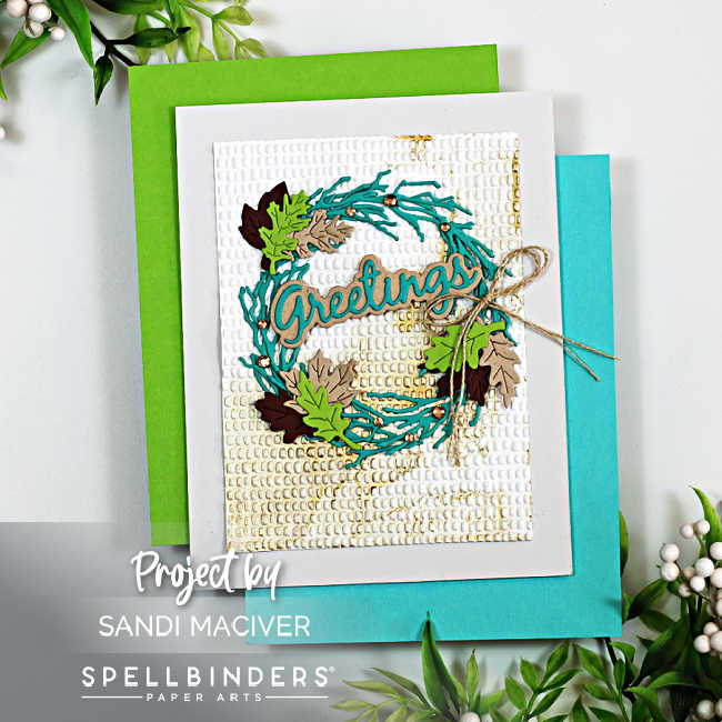Handmade fall-themed greeting card created with the Spellbinders Autumn Greetings Wreath Die Set and Dimpled 3D Embossing Folder. The card features a layered teal twig wreath embellished with die-cut leaves in shades of green, brown, and tan, accented with tiny copper pearls. The sentiment “Greetings” is centered across the wreath in teal and kraft cardstock. The background is embossed with a textured dimple pattern, framed in white, and finished with a natural twine bow on the right side. The card is displayed on aqua and green cardstock layers with greenery accents around the edges.
