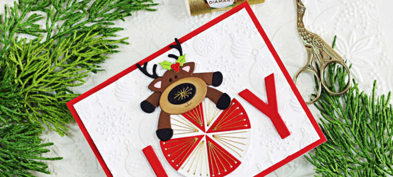 Handmade Christmas card created with the Spellbinders Stitched Die of the Month Club, featuring a stitched red and gold circle forming the letter O in the word JOY, with a die-cut reindeer sitting on top. The background is embossed with the Spellbinders Season Sparkles Embossing Folder, and the card is layered on a bright red base for festive dimension