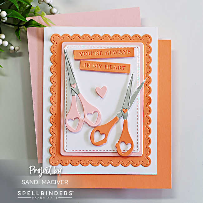Handmade card created with the Spellbinders Sharon’s Scissors Die Set in honor of Sharon Klima for World Fussy Cutting Day. The design features two pairs of heart-handled scissors in soft pink and coral tones arranged on layered scalloped and stitched rectangle panels. A small heart embellishment and the sentiment “You’re Always in My Heart” complete the layout, symbolizing creativity, friendship, and heart health awareness.