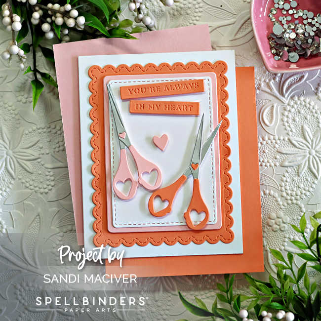 Handmade card created with the Spellbinders Sharon’s Scissors Die Set in honor of Sharon Klima for World Fussy Cutting Day. The design features two pairs of heart-handled scissors in soft pink and coral tones arranged on layered scalloped and stitched rectangle panels. A small heart embellishment and the sentiment “You’re Always in My Heart” complete the layout, symbolizing creativity, friendship, and heart health awareness.