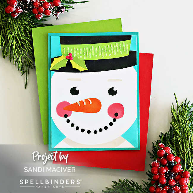 Handmade Frosty snowman Christmas card created with the Spellbinders Stencil of the Month Club ‘Frosty Wishes.’ Features a cheerful snowman face with a carrot nose, rosy cheeks, and a green top hat accented with holly, layered on a bright turquoise card base for a fun and festive holiday design.