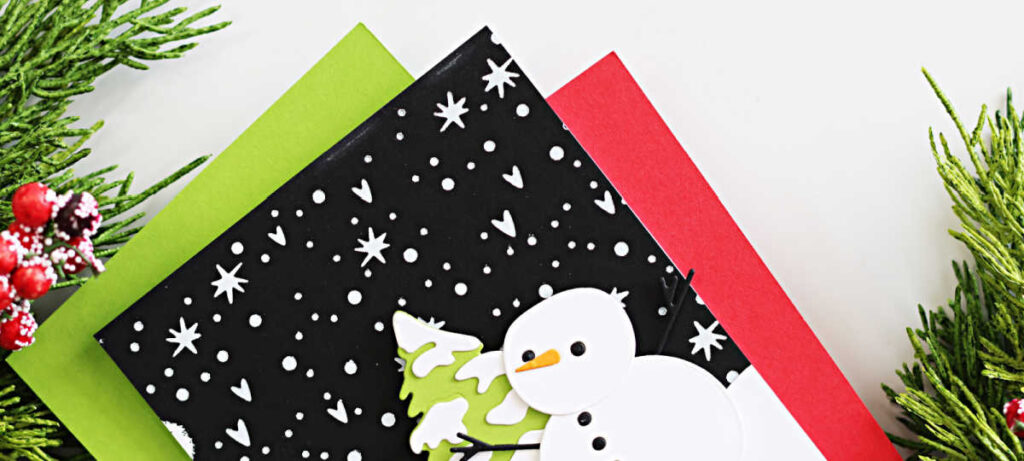 Handmade Christmas card created by Sandi MacIver featuring the Spellbinders October 2025 Small Die of the Month “Snow Day Friends.” The card showcases a layered white die-cut snowman and tree on a snowy black background hot foiled in white with the Magic Wonderland October Glimmer Club plate. The sentiment “All is calm & bright” from the To You and Yours October Clear Stamp and Die Set is stamped on a curved white snowbank. Clean and modern design in classic holiday colors with pops of lime green and red.