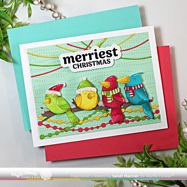 Handmade Christmas card created with the Waffle Flower Birdie Friends dies and coordinating stencils. The design features four colorful, ink-blended birds—green, yellow, red, and blue—each wearing festive winter hats and scarves, perched on a branch against a pale mint background embossed with the Wood Grain Texture die. Strands of stitched Christmas lights arch playfully overhead, and the bold sentiment “Merriest Christmas” from the Warm Wishes stamp and matching piercing die set is centered above the birds. The card is displayed atop red and aqua cardstock with holiday greenery accents.