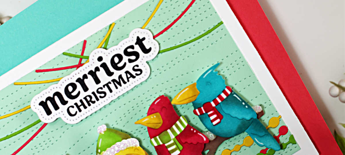 Handmade Christmas card created with the Waffle Flower Birdie Friends dies and coordinating stencils. The design features four colorful, ink-blended birds—green, yellow, red, and blue—each wearing festive winter hats and scarves, perched on a branch against a pale mint background embossed with the Wood Grain Texture die. Strands of stitched Christmas lights arch playfully overhead, and the bold sentiment “Merriest Christmas” from the Warm Wishes stamp and matching piercing die set is centered above the birds. The card is displayed atop red and aqua cardstock with holiday greenery accents.