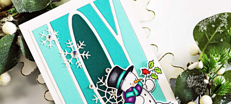 Handmade Christmas card featuring the Simon Says Stamp Joy Cover Die in layered teal ombré cardstock, accented with delicate white Harmony Snowflakes and clear gems. A Copic-colored snowman from the Cozy in the Cold stamp set stands at the bottom right holding a holly sprig with a red bird. Card displayed upright on white wooden snowflake risers with winter greenery and a blue ornament in the background.