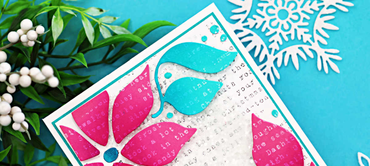Handmade Christmas card featuring a bold poinsettia design die-cut in bright pink and aqua cardstock. The background is stamped with a light gray text print and topped with Distress Grit Paste and chunky glitter for a snowy mixed-media texture. Aqua enamel dots are added as accents, and the card is layered onto a white and teal cardstock frame for a modern holiday look.