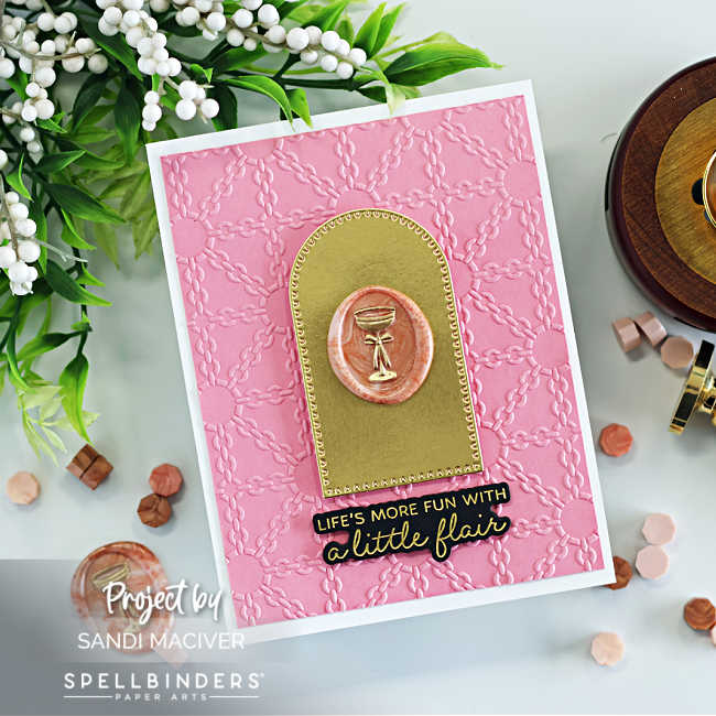 A handmade pink card created with the Spellbinders November Clubs featuring a luxe chain-style background embossed with the Luxe Lattice Embossing Folder. The focal point is a gold arched frame with a marbled coral wax seal stamped with a gold champagne glass design from the Cin Cin Wax Seal of the Month. Below the wax seal is a black and gold sentiment from the BetterPress Club “Paws in the City” set that reads: “Life’s more fun with a little flair.” The card is displayed flat lay style with wax beads, a wax seal tool, and greenery styled around it.