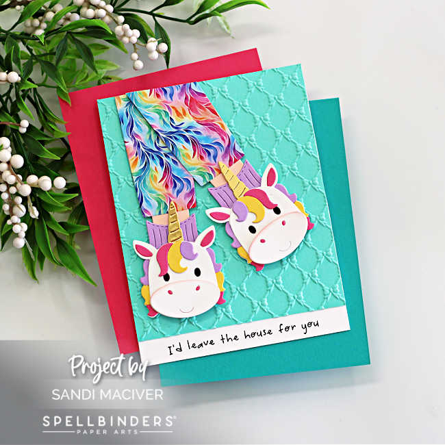 Handmade unicorn slipper card created with the Spellbinders Cozy Toes Friends Die Set and embossed using the Petite Bows 3D Embossing Folder. The card features colorful rainbow pajama pants tucked into whimsical unicorn slippers layered over an aqua embossed background with a playful sentiment strip that reads “I’d leave the house for you.” Designed by Sandi MacIver for Spellbinders Paper Arts.