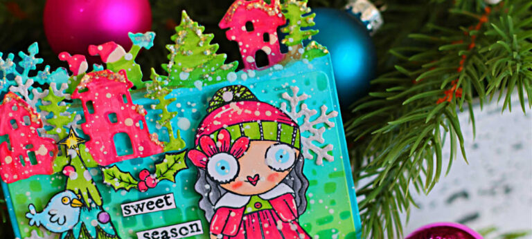 Colorful Memory Dex die card featuring AALL & Create products, with a whimsical Christmas scene on a teal and green background. The card includes a hand-colored Miss Merry character in a red dress and striped tights, pink houses along the top edge, green trees, small birds, holly leaves, snowflakes, and white paint splatter. The words “sweet season” are centered on the card, and the project is photographed among evergreen branches and bright holiday ornaments.