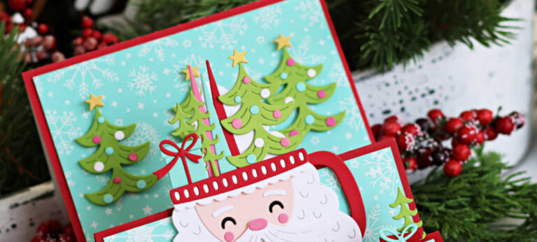 Handmade landscape stair-step Christmas card featuring a die-cut Santa mug and three layered Christmas trees. The card is created using Spellbinders Cocoa Wonderland dies and sits on a red card base with a snowflake-patterned aqua background created with the Snowflake Shimmer BetterPress Plate. Santa has a white layered beard, pink cheeks, and a red handle with Christmas Decor popping out. A “Merry Christmas” sentiment is displayed on the front step along with a small die-cut bow and gift. The coordinating card in the background also features Christmas trees and the same snowflake aqua background.