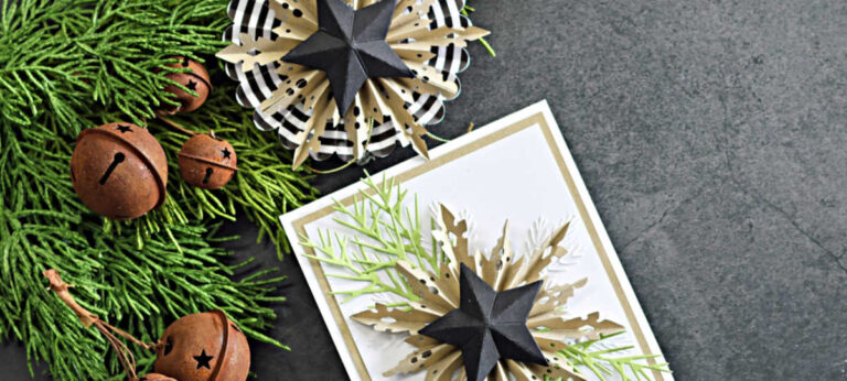 A handmade holiday card featuring layered dimensional snowflake rosettes created with the Tim Holtz Snowflake Rosette and Vault Rosettes dies for Simon Says Stamp DieCember. The main card displays a large kraft and white die-cut rosette topped with a bold black 3D star and accented with die-cut evergreen branches. Surrounding the card are two additional coordinating rosettes—one plaid and one white—each finished with matching black stars. The scene is styled on a dark background with fresh greenery and rustic brown jingle bells for a festive winter look.