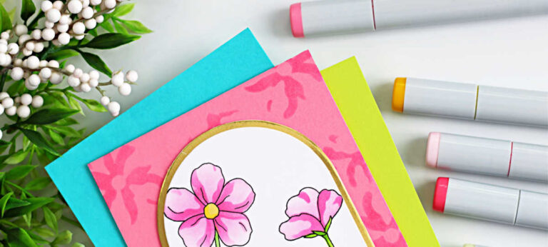 Handmade spring card featuring a white bunny standing in green grass and looking up at pink flowers inside a gold-trimmed arched window. Two pastel Easter eggs sit at the bunny’s feet. The scene is layered over a pink stenciled background with teal and lime cardstock mats, photographed on a white surface with alcohol markers and greenery accents.