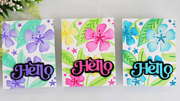Three handmade A2 cards created using the Altenew Joyful Garden products featuring a stencil over embossing technique. Each card showcases layered floral stenciling applied over an embossed background for added texture and dimension. The designs include large hibiscus-style flowers and leafy greenery in three colorways: soft purple and mint, bright pink and yellow, and vibrant teal and blue. Each card features a bold, layered “Hello” sentiment in coordinating colors centered across the floral panel.