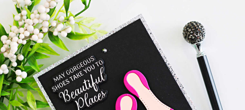 Handmade card featuring bright fuchsia high-heel shoes created with the Alex Syberia Designs Chic Shoes Die Set, each finished with silver glitter bows. The shoes are layered on a black card front with a silver glitter frame, and a white BetterPress sentiment from the Shoes Sentiments BetterPress Plates reads “May gorgeous shoes take you to beautiful places.” Small crystal gems add sparkle to this elegant fashion-themed card.