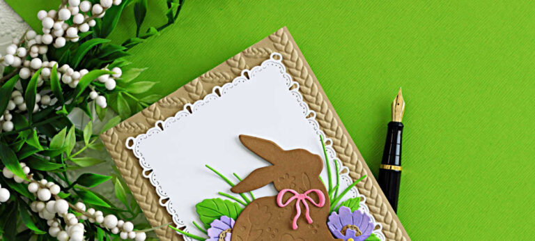 Die cut Easter bunny card featuring Simon Says Stamp Embellished Bunny on a white Ribbon Loop Frames panel with layered flowers and a kraft embossed background