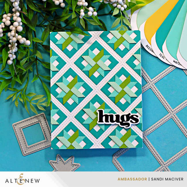 Handmade die cut quilt card featuring a teal and green geometric pattern created with Altenew Patchwork Pathways dies, finished with a layered “hugs” sentiment on a white lattice background.