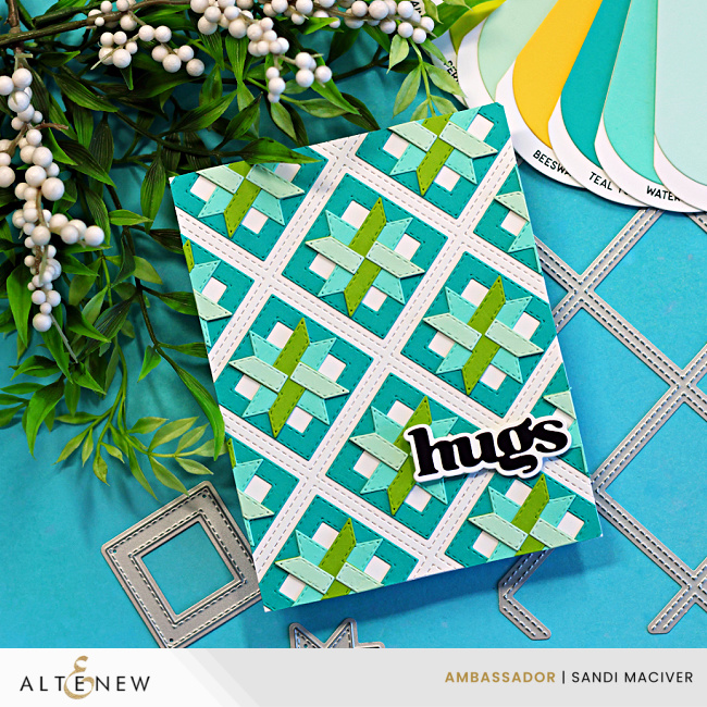 Close-up of a handmade die cut quilt card featuring a teal and green geometric pattern created with Altenew Patchwork Pathways dies, finished with a layered “hugs” sentiment on a white stitched lattice background.
