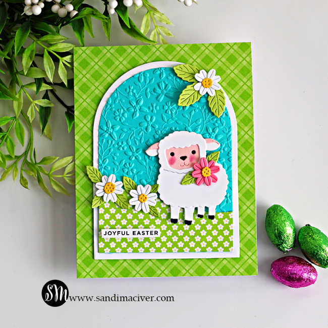 Spring Easter card with a sweet lamb holding a flower, created with the Simon Says Stamp Sweet Sheep die, A2 Arches dies, embossed background and layered floral accents.