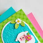 Handmade Easter lamb card created with the Simon Says Stamp Sweet Sheep die and A2 Arches dies, featuring a white sheep holding a flower on an embossed turquoise arch background with daisies and green patterned paper.