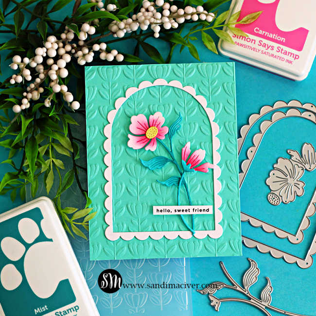 Elegant handmade floral arch card with pink die cut flowers on an aqua embossed background, layered with a scalloped frame and styled with greenery
