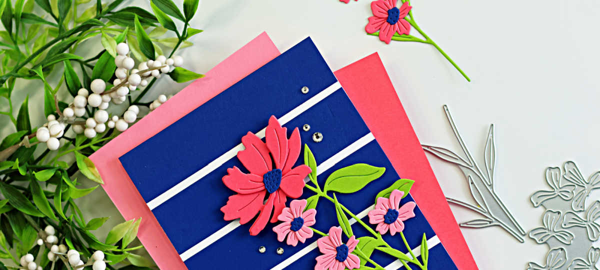 Bold cardmaking color combo featuring a navy background with pink die cut flowers, green leaves, and white stripe details, creating a dramatic floral handmade card design.