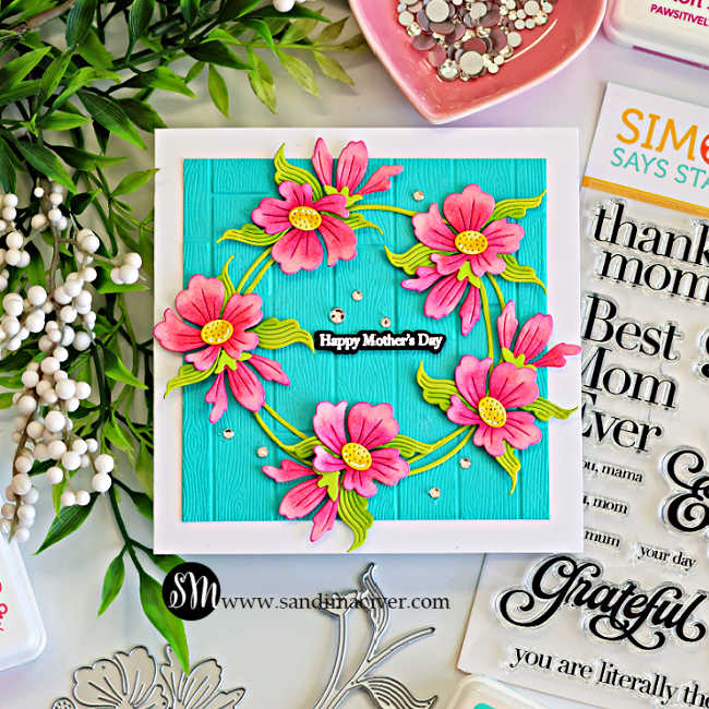 Square Mother’s Day card with pink ink-blended die cut flowers forming a wreath on Audrey Blue cardstock embossed with a wooden plank texture, featuring a “Happy Mother’s Day” sentiment.