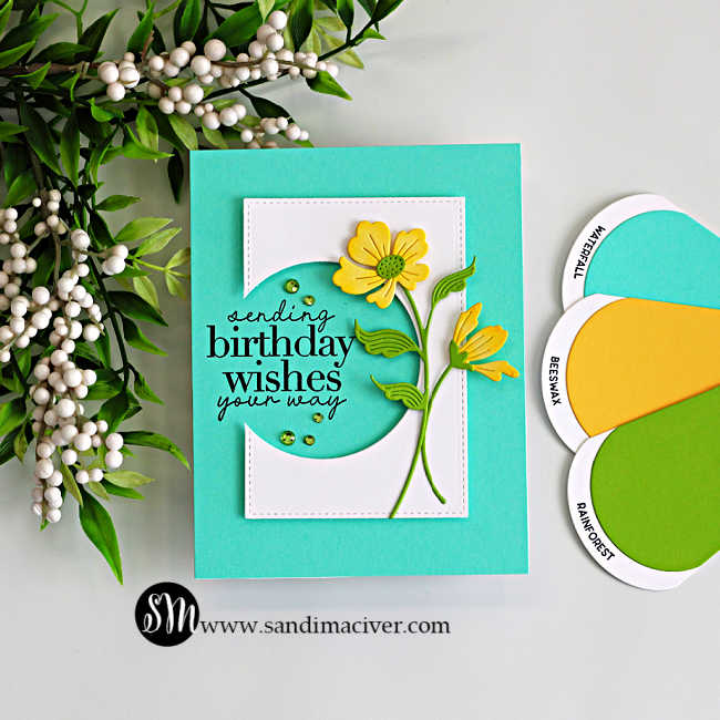 Handmade floral birthday card featuring a circle die cut window with “sending birthday wishes your way” sentiment, layered yellow flowers, teal background, and green cardstock accents for an easy cardmaking technique