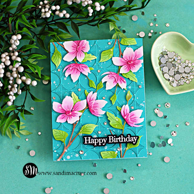 Die cut spring card with elegant blossom branch, featuring pink layered flowers, green leaves, and a teal embossed background with a Happy Birthday sentiment.