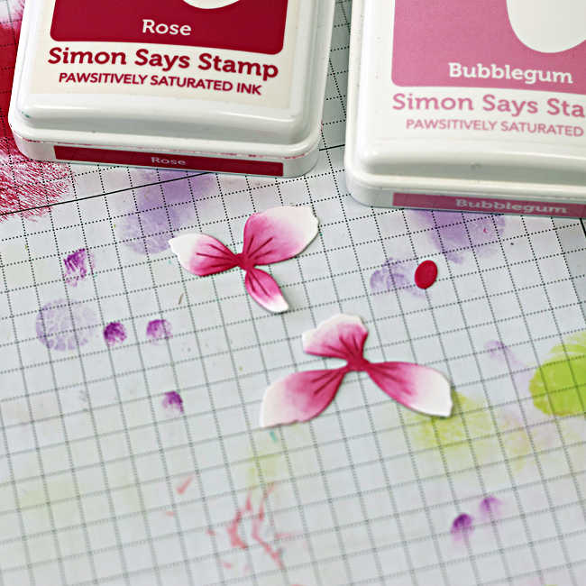 Ink blending die cut flower petals for a die cut spring card using pink inks on a craft mat.